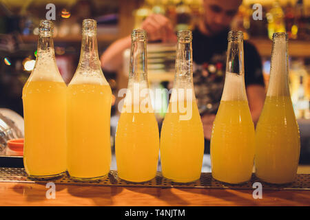 Sechs Flaschen frische Limonade auf einem Holztisch auf der Bar. Stockfoto