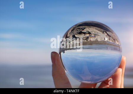 Morecambe Bay an einem klaren Frühlingstag, Lancashire, UK, als durch einen Kristall fotografie Kugel in eine weibliche Hand gesehen - Brechung Fotografie Stockfoto