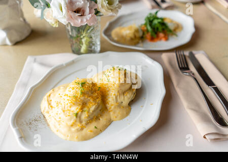 Ei Benedikt auf warmen Toast Brioche. Zwei Eier, leckeren Sauce Hollandaise. Licht am Morgen das Frühstück auf dem Tisch im Restaurant. Stockfoto