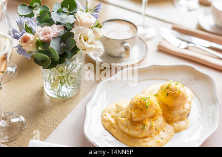 Ei Benedikt auf warmen Toast Brioche. Zwei Eier, leckeren Sauce Hollandaise. Licht am Morgen das Frühstück auf dem Tisch im Restaurant. Stockfoto