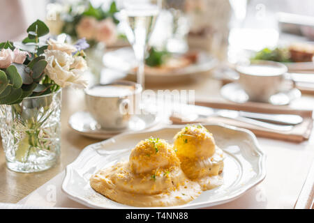 Ei Benedikt auf warmen Toast Brioche. Zwei Eier, leckeren Sauce Hollandaise. Licht am Morgen das Frühstück auf dem Tisch im Restaurant. Stockfoto