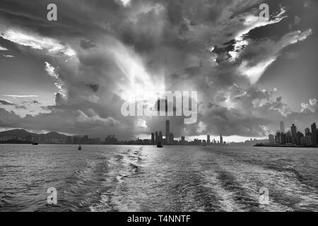 Moody Schwarz-weiß-Foto Einer riesigen tropischen Sturmwolke (Cumulonimbus), beleuchtet von der aufgehenden Sonne, über Victoria Harbour, Hongkong. Stockfoto