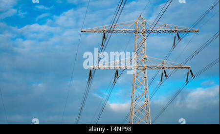 Elektrische Leitungen gegen einen blauen Himmel mit Wolken im Winter in den Niederlanden Stockfoto