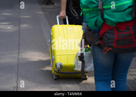 Gelbe Reisekoffer von Hand gezogen auf der Straße. Konzept für Reise Stockfoto