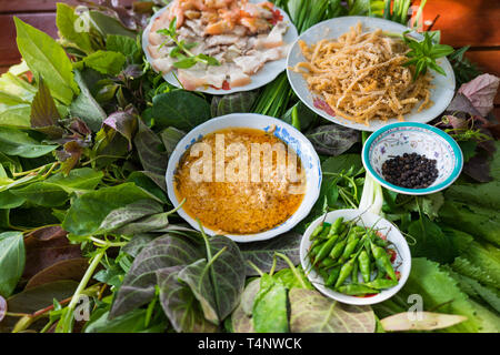 Besondere Kräuter Salat in Kon Tum, Vietnam. Mit den Blättern, um einen kegelförmigen Behälter das Essen zu bringen, und einige Speck, gebratene Garnelen, Slice Stockfoto