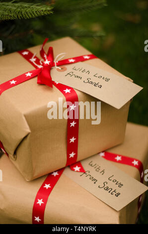 Zwei Weihnachtsgeschenke in braunem Papier mit roter Schleife verpackt Stockfoto