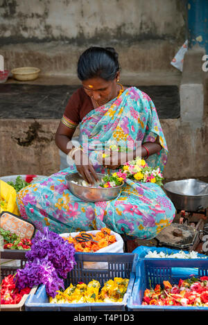 Vertikale Ansicht einer Dame bei der Arbeit die Girlanden an Mattuthavani Blumenmarkt in Madurai, Indien. Stockfoto