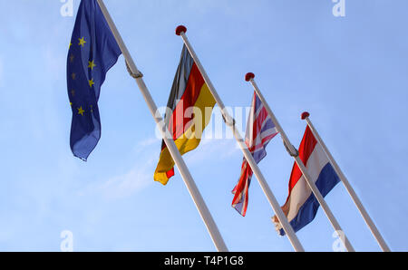 Flaggen aus England, Vereinigtes Königreich, Deutschland und Nederlands winken von fahnenmasten zusammen mit der EU, Europäische Union, Flagge gegen einen blauen Himmel. Stockfoto