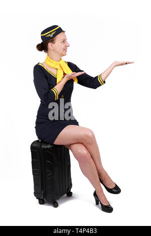 Stewardesse - charmant und lächelnden Stewardess In der blauen Uniform sitzen auf Ihrem Koffer gekleidet. Auf weissem Hintergrund Stockfoto