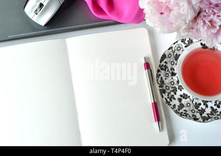 Elegant Gestalteten weiblichen Desktop - Entspannung, Lesen, kreatives Schreiben, Lernen und Journaling Konzept mit rosa Pfingstrosen, Obst Kaffee schickes Zubehör Stockfoto