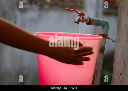 Junge Hände Sammeln von Wasser mit einem Eimer aus einem alten langsam fließenden Wasser Stockfoto