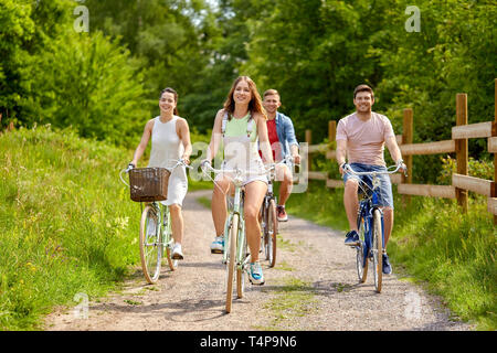 Menschen, Freizeit und Lifestyle Konzept - glückliche junge Freunde, fixed Gear, Fahrräder auf Landstraße im Sommer Stockfoto