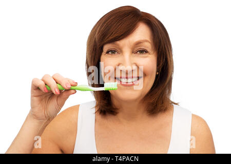 Zahnpflege und hygiene Personen Konzept - Porträt von lächelnden älteren Frau mit Zahnbürste ihre Zähne putzen auf weißem Hintergrund Stockfoto