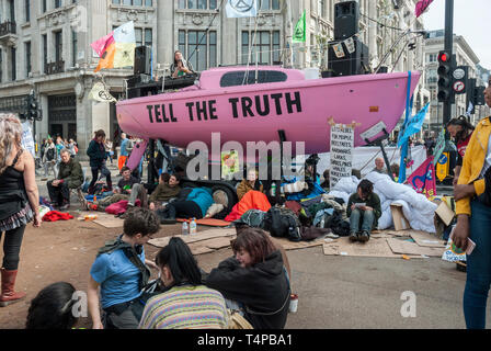 "Demonstranten Aussterben Rebellion" gegen den Klimawandel blockieren und Oxford Circus mit einem hellen Rosa Yacht zeigt eine "Wahrheit" einfach besetzen. Stockfoto