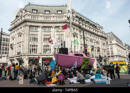 "Demonstranten Aussterben Rebellion' und Unterstützer gegen den Klimawandel blockieren und Oxford Circus, London, mit einem hellen Rosa Yacht belegen. Stockfoto