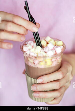 Marshmallow Kakao in eine Schale mit zwei Röhren in der Hand einer Frau Stockfoto