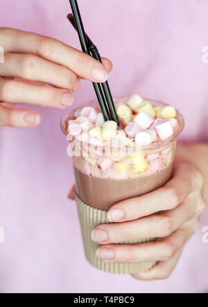 Marshmallow Kakao in eine Schale mit zwei Röhren in der Hand einer Frau Stockfoto