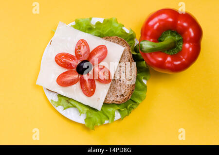 Sandwich mit Gemüse auf einem weißen Teller auf gelbem Hintergrund Stockfoto