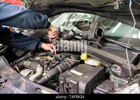 Mechaniker arbeitet an einem Auto Motor Reparatur oder Wartung Wartung in einer Detailansicht der Hände mit einem Schraubendreher Stockfoto