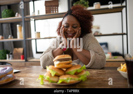 So hungrig. Fröhliche Frau Positivität Ausdruck beim Gehen fast food zu essen Stockfoto