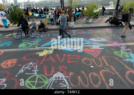 Menschen zu Fuß auf Graffiti von Demonstranten, die Waterloo Bridge in London während das Aussterben Rebellion Streik in London gesperrt. Umweltaktivisten vor dem Aussterben Aufstandsbewegung halten für vierten aufeinander folgenden Tag der Waterloo Bridge in London. Aktivisten wurde ein Lkw auf der Brücke die Straße blockieren, wodurch Unterbrechungen geparkt. Polizei verhaftete Demonstranten, die zu Marble Arch zu verweigern. Aussterben Rebellion fordert von der Regierung direkte Aktionen auf das Klima, die CO2-Emissionen bis 2025 auf Null zu reduzieren und die Völker. Stockfoto