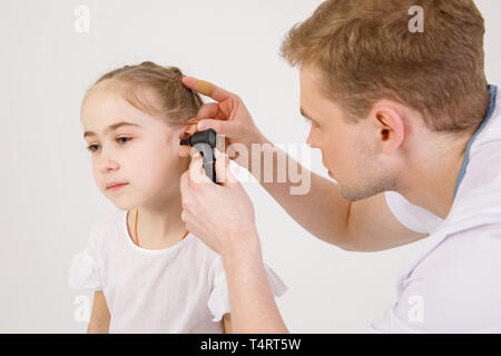 Die junge sympathische otolaryngologist untersucht die Ohren der ein Mädchen - ein Mädchen im schulpflichtigen Alter, Stockfoto