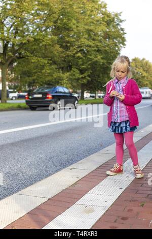 Mädchen (6) am Straßenrand, Kiel, Deutschland, Europa Stockfoto