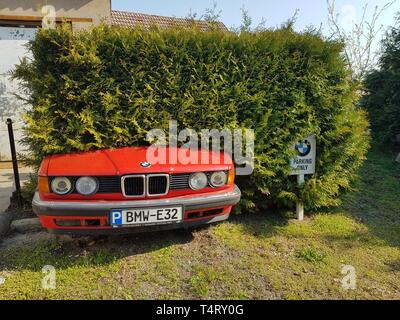 Ostritz, Sachsen/Deutschland - 6. April 2019. Spezielle Parkplatz für BMW-Fahrzeugen vorbehalten. Lustig, weil der alte BMW E32 stecken in einer Hecke Stockfoto