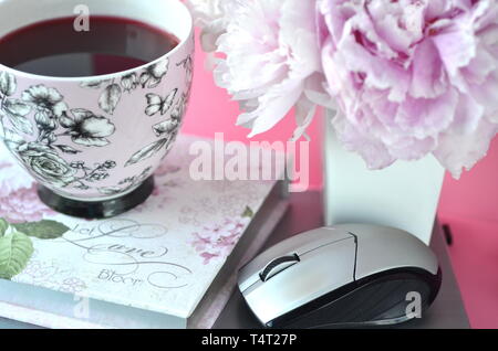 Elegant Gestalteten weiblichen Desktop - Entspannung, Lesen, kreatives Schreiben, Lernen und Journaling Konzept mit rosa Pfingstrosen, Kaffee, schickes Zubehör Stockfoto