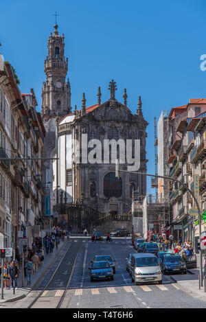Blick auf die Carmo-Kirche und den Clérigos-Turm in Porto, Portugal, mit Verkehr und Menschen entlang einer belebten Straße an einem sonnigen Tag Stockfoto
