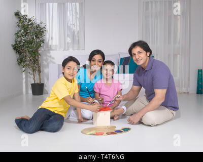 Indische FAMILIE VON 4 Malerei ein Spielzeug HAUS IN IHREM HAUS Stockfoto