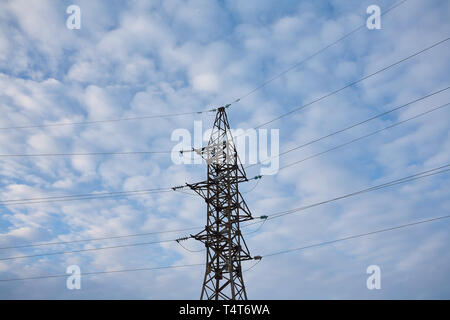 Unterstützt die Hochspannungs-Leitungen gegen den blauen Himmel mit Wolken. Elektro-Industrie. Stockfoto