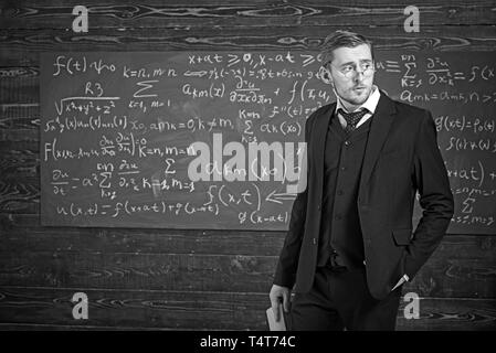 Junge Adelige in Gläsern holding Buch und im Klassenzimmer aufwerfen. Elite Bildung Konzept. Stockfoto