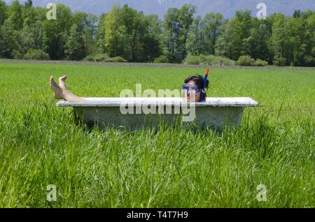 Frau in einer Badewanne, mit Taucherbrille, grüner Bereich Stockfoto