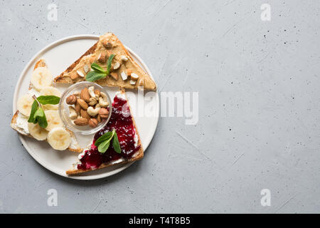 Drei zuckerfreie Brötchen zum Frühstück, Mutter einfügen, Bananen, Beeren Marmelade. Platz für Text. Ansicht von oben. Stockfoto