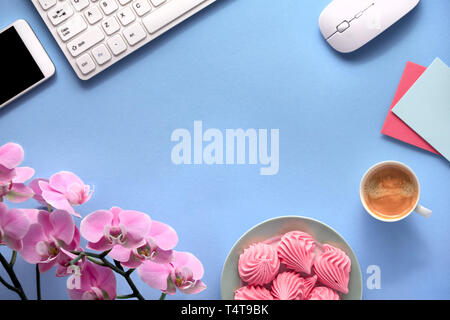 Phalenopsis rosa Orchidee, Grußkarten, Tastatur, Mobiltelefon, Platte der Eibisch und Tasse Kaffee. Flach auf blauem Papier Hintergrund mit copy-s Stockfoto