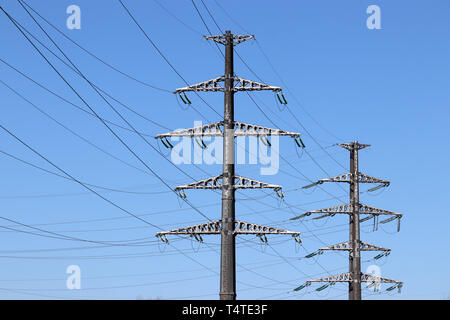 Power Line unterstützt mit elektrischen Kabeln am klaren, blauen Himmel Hintergrund. Hohe Spannung Fernleitungen, Konzept der Stromversorgung Stockfoto