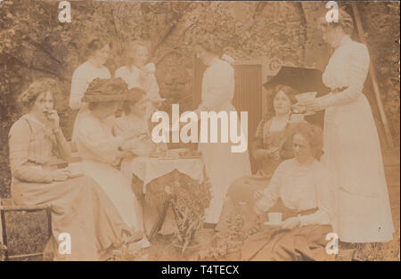 Vintage Edwardian photographische Postkarte zeigt eine Gruppe von Damen in einem Garten Tea Party. Stockfoto