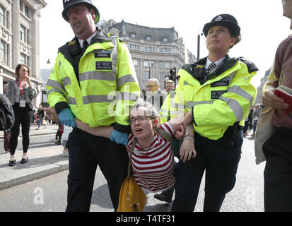 Ein Klima Aktivist wird von Polizisten aus einem Aussterben Rebellion Demonstration am Oxford Circus, London durchgeführt. Londoners Gesicht der vierte Tag der Unterbrechung in der Hauptstadt, die trotz der fast 400 Festnahmen. Stockfoto