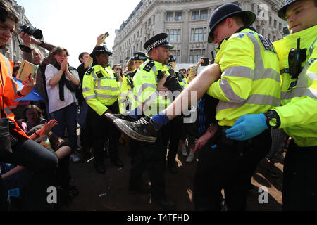 Ein Klima Aktivist wird von Polizisten aus einem Aussterben Rebellion Demonstration am Oxford Circus, London durchgeführt. Londoners Gesicht der vierte Tag der Unterbrechung in der Hauptstadt, die trotz der fast 400 Festnahmen. Stockfoto