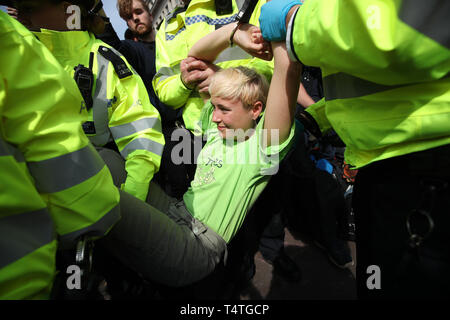 Ein Klima Aktivist wird von Polizisten aus einem Aussterben Rebellion Demonstration am Oxford Circus, London durchgeführt. Londoners Gesicht der vierte Tag der Unterbrechung in der Hauptstadt, die trotz der fast 400 Festnahmen. Stockfoto