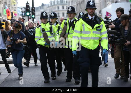 Ein Klima Aktivist wird von Polizisten aus einem Aussterben Rebellion Demonstration am Oxford Circus, London durchgeführt. Londoners Gesicht der vierte Tag der Unterbrechung in der Hauptstadt, die trotz der fast 400 Festnahmen. Stockfoto