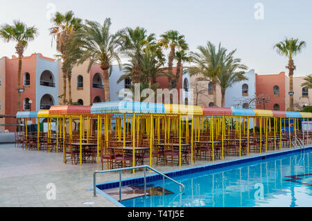 Das hölzerne Restaurant Terrasse mit 4-sitzer Tische mit einem kleinen Dach vor der Sonne entlang der Pool Stockfoto