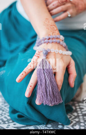 Frau mit lila mala Perlen auf Ihre Hände mit Henna mehendi Stockfoto