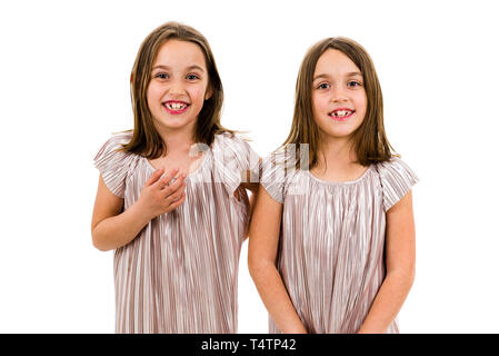 Identische Zwillinge Schwestern sind posieren für die Kamera. Happy Zwillingsschwestern in Kleider betrachten die Kamera und lächelnd. Vorderansicht, Studio shot Stockfoto