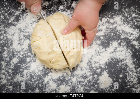 Schneiden ein großes Stück Teig auf einer mit Mehl für die Herstellung von Quark cookies Stockfoto