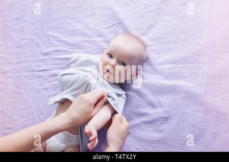 Übergeordnete Krankenschwester ändern Windeln für neugeborene Tochter Sohn Kind. Eltern Babysitter kümmert sich um Kind und setzen auf Kleidung Body. Das authentische Leben Stockfoto