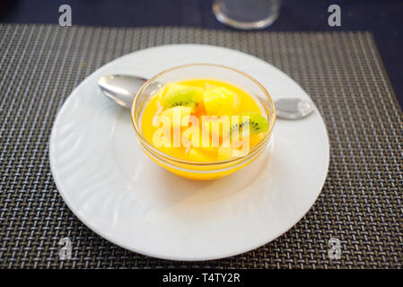 Gläschene Schale mit frischem Obstsalat aus Orange, Kiwi und Ananas auf einem weißen Teller, Madrid, Spanien Stockfoto