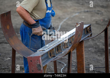 Arbeitnehmer mit Schleifer, um Rost aus Metall an der Baustelle. Stockfoto