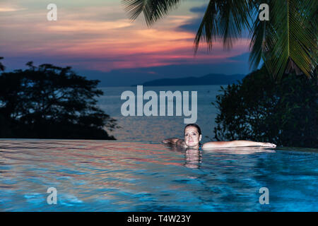 Eine Frau, die am Rande der einen Pool mit Meerblick Stockfoto